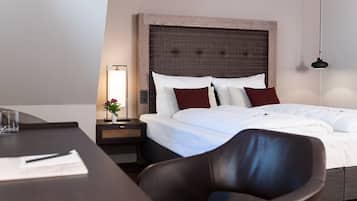 Een hotelkamer met een groot bed, een nachtkastje met een lamp, een stoel en een bureau.