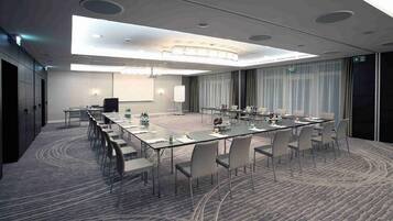 A conference room with a long table, chairs, a projector, and a screen.