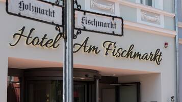 A hotel entrance with signs indicating 'Hotel Am Fischmarkt' and 'Fischmarkt'.