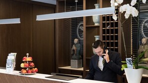 A reception desk with a fruit display, a vase with white orchids, and a statue.