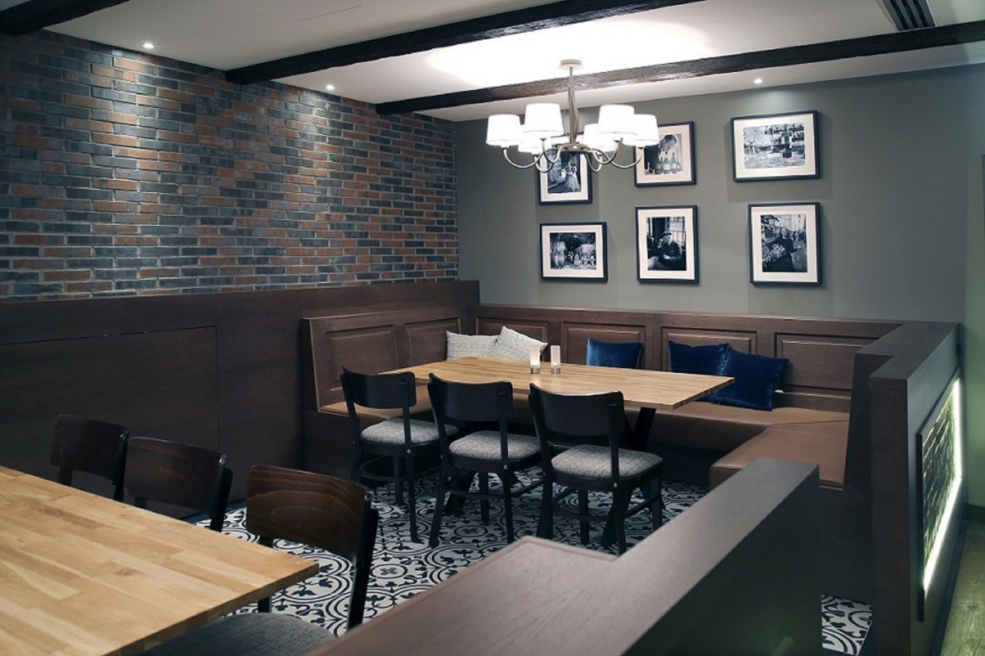 A dining area with a brick wall, a chandelier, and framed pictures on the wall.