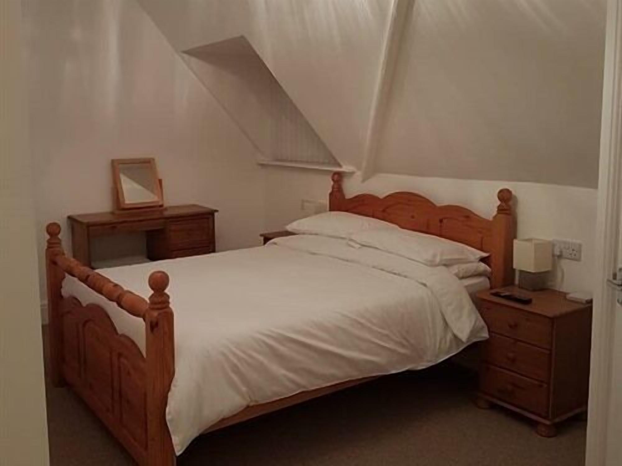 Un dormitorio con una cama de madera, una mesita de noche, un aparador y un espejo.