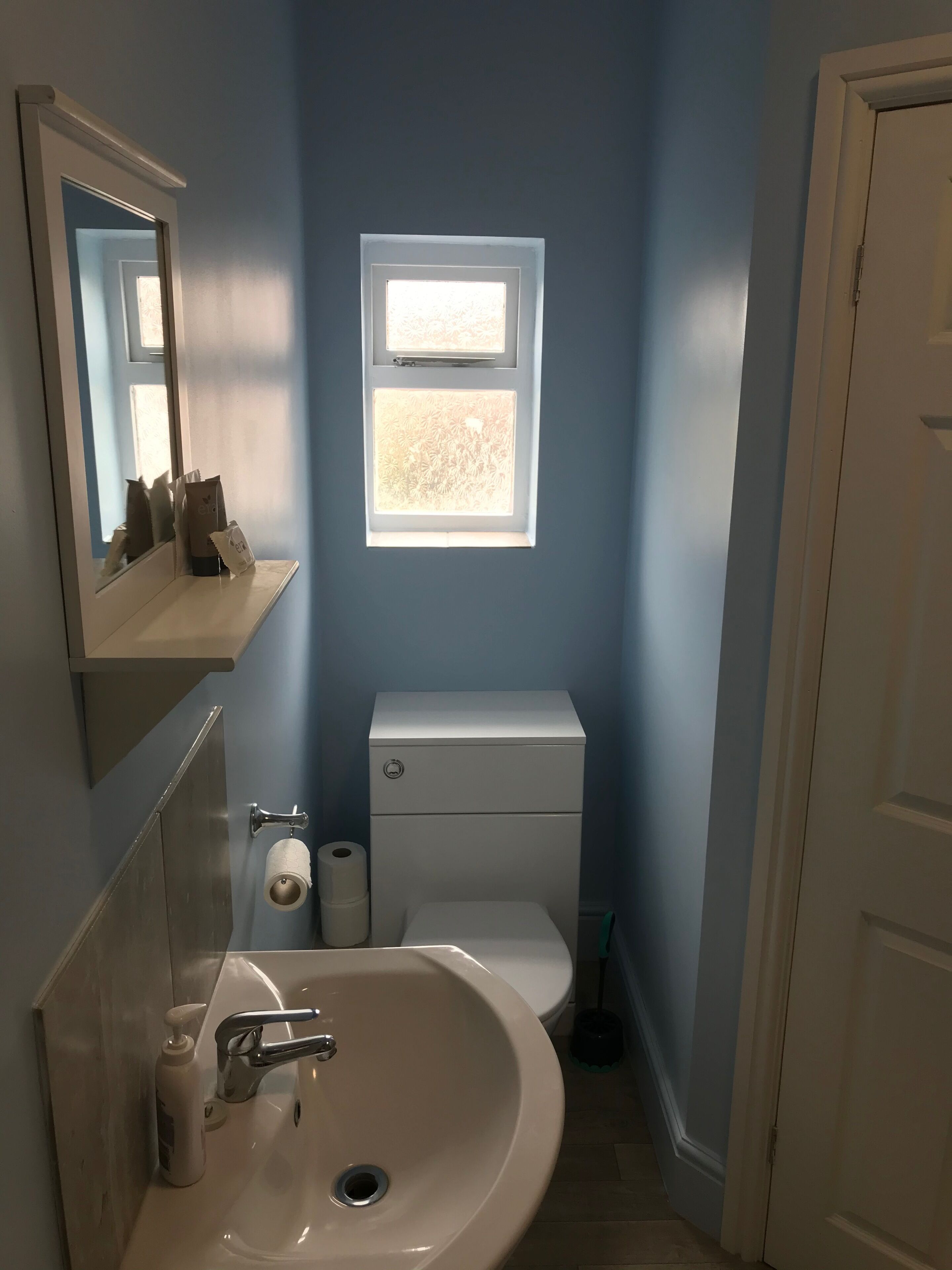 A bathroom with a sink, toilet, and window.