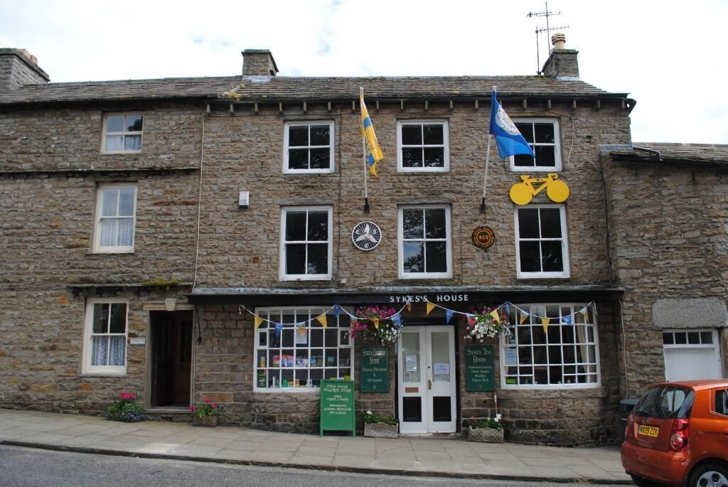 A stone building with a sign reading 'SYKES'S HOUSE' and a bicycle symbol.