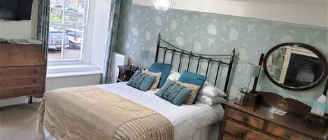 A bedroom with a bed, dresser, window, and chandelier.
