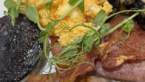 A plate of food with scrambled eggs, mushrooms, bacon, and a slice of black pudding. - Sykes's House (Leyburn)