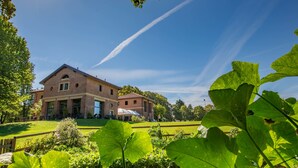 A large brick building with a symmetrical facade, a covered outdoor seating area, and a well-maintained lawn. - Ostello Costa Alta (Monza)