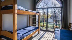 A bunk bed room with a large window and a view of trees. - Ostello Costa Alta (Monza)