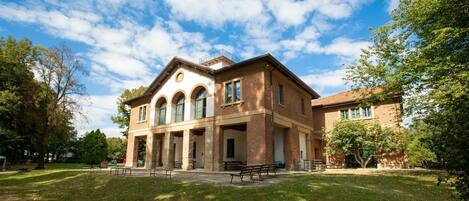A large brick building with multiple windows and a covered porch area.