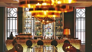 Una zona de bar con mostrador, estanterías llenas de botellas y un muro decorado.