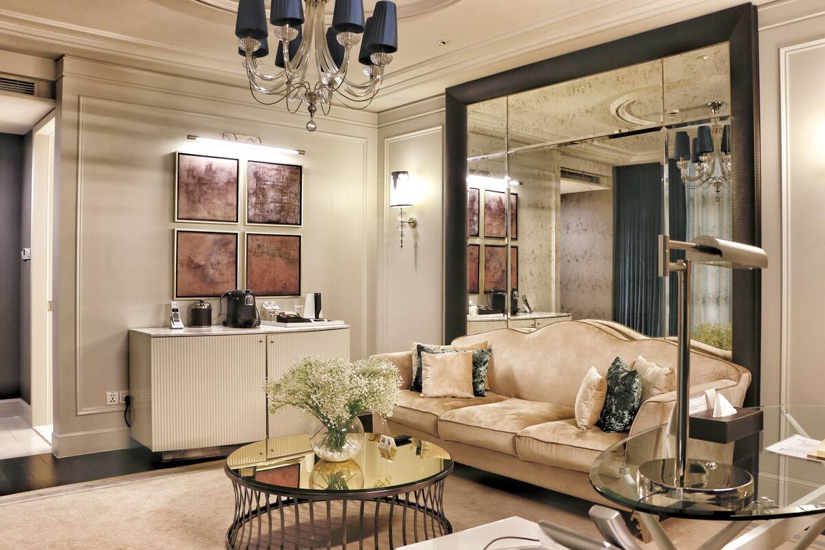 Una sala de estar moderna con un sofá color beige, una mesa de centro de vidrio y un espejo grande.