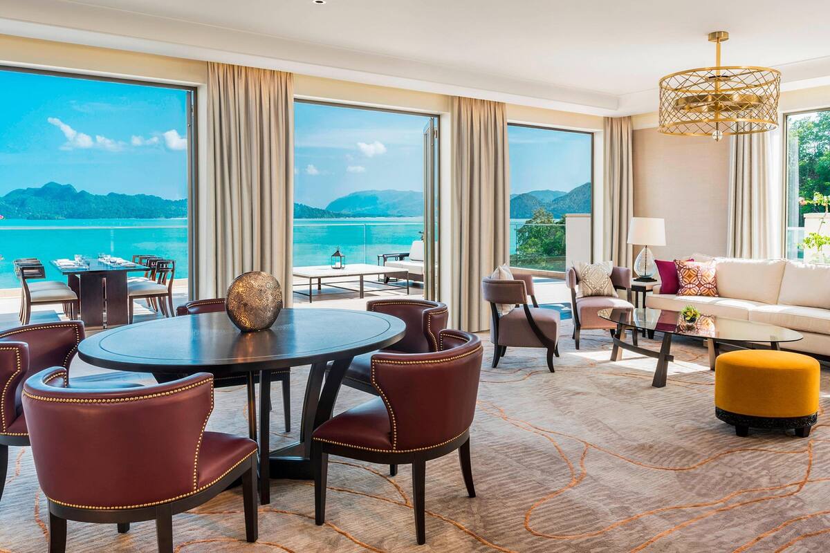 Une pièce spacieuse avec une grande table à manger, des sièges confortables, un canapé et une vue sur la mer.