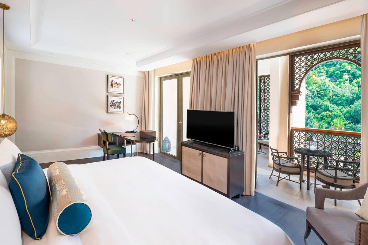 Une chambre d’hôtel équipée d’un lit, d’une télévision, d’un bureau et d’un balcon avec des meubles d’extérieur.