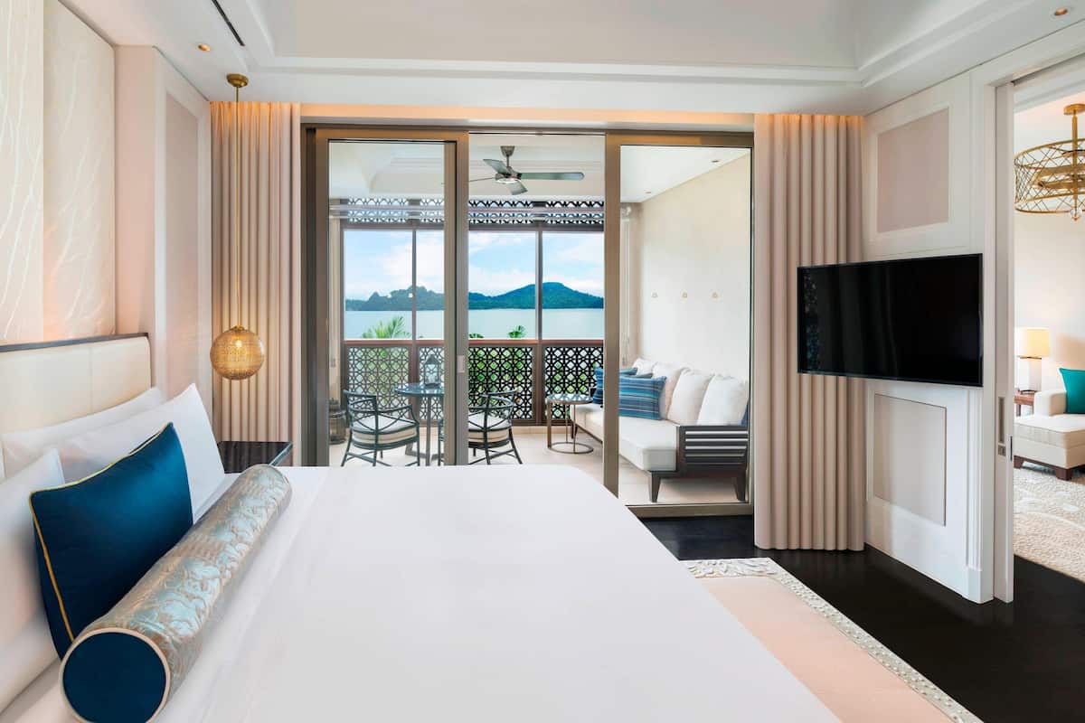 Une chambre d’hôtel dotée d’un grand lit, d’une télévision, d’un balcon avec vue sur les montagnes et d’un coin repas.