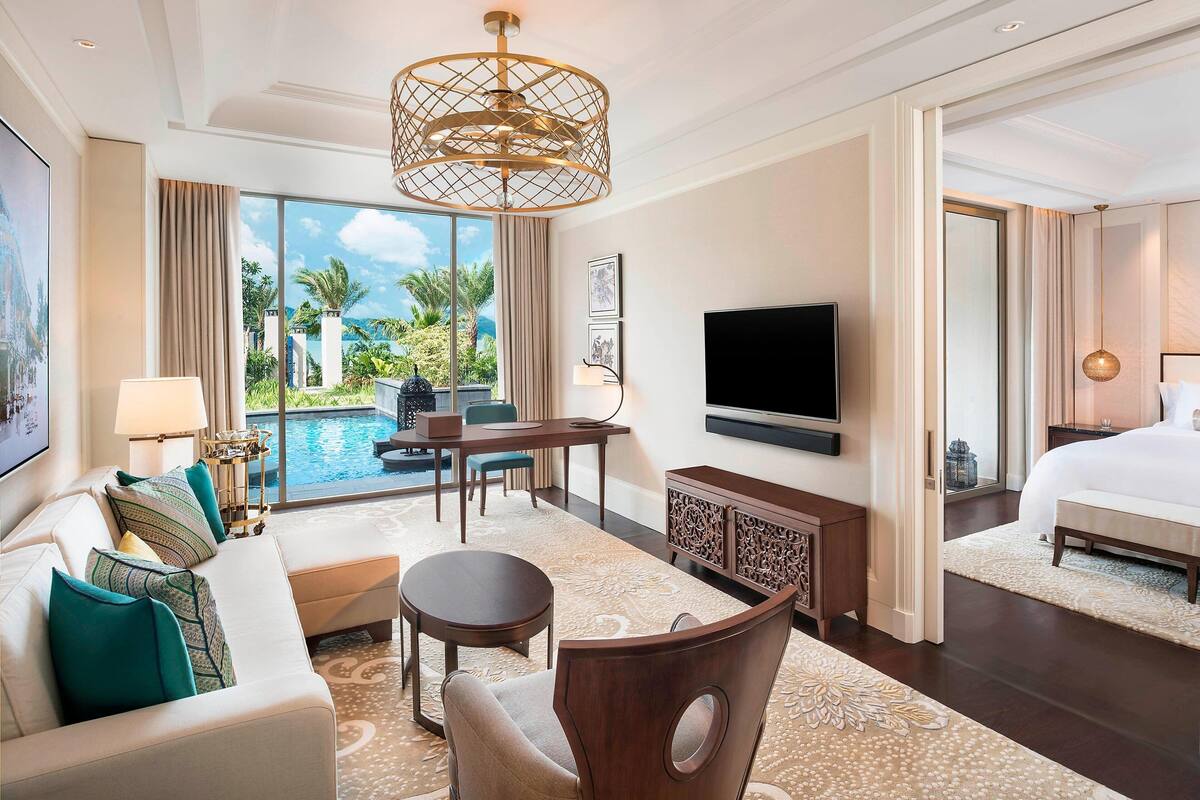 Une chambre d’hôtel équipée d’un canapé, d’une table à manger, d’une télévision, d’un lit et offrant une vue sur l’extérieur.