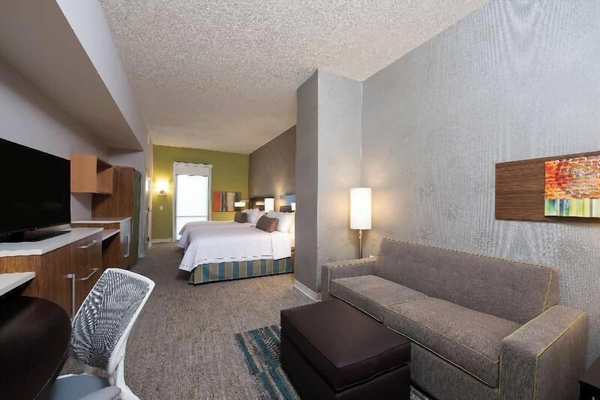 Une chambre d’hôtel avec un lit, un canapé, une télévision, un bureau et une chaise.