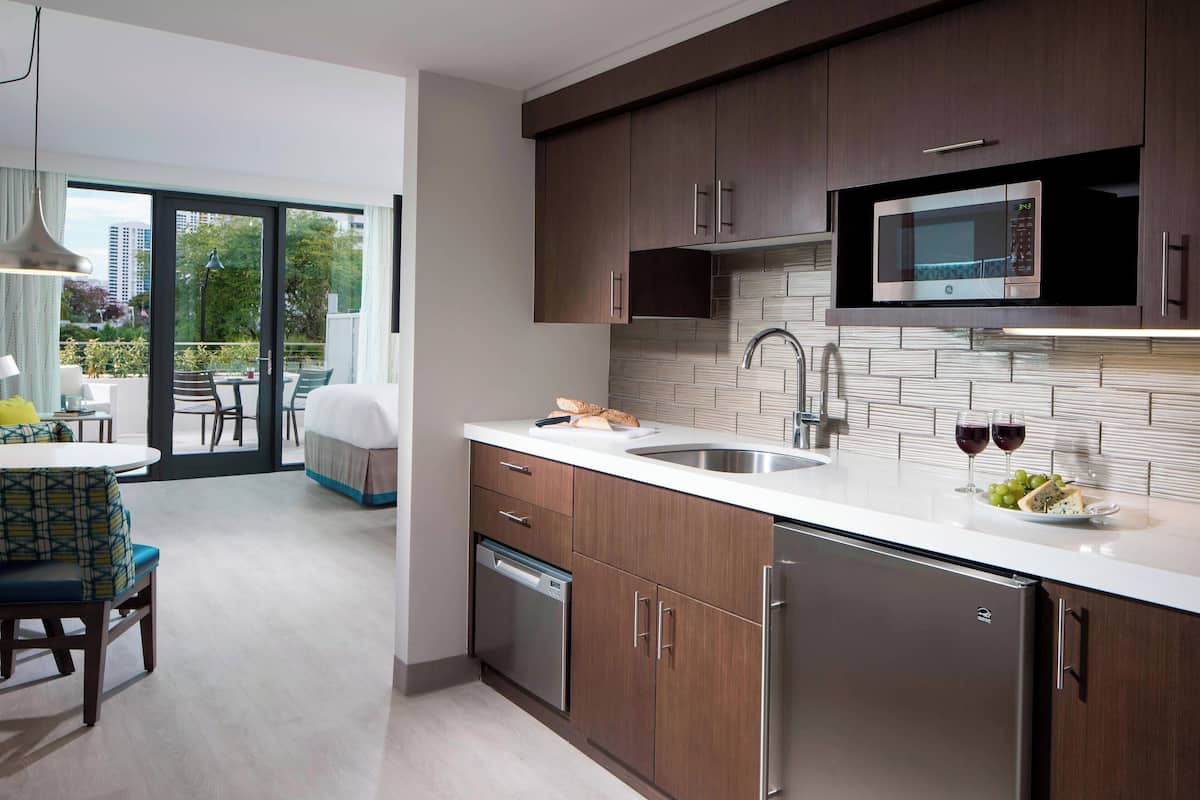 A modern kitchen with stainless steel appliances, a large window, and a dining area with a view.