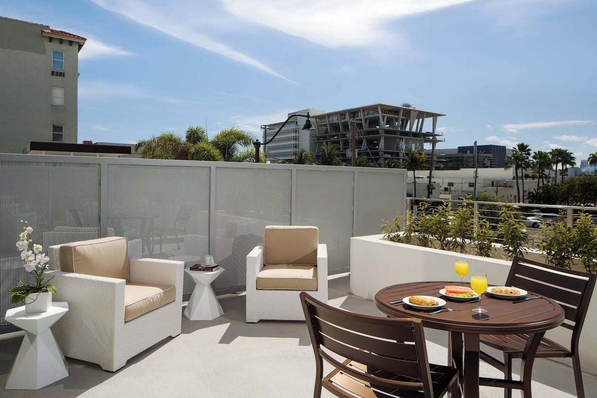 A rooftop patio with outdoor furniture, including a table and chairs, and a potted plant.