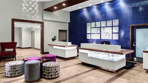 A reception area with a blue accent wall, a reception desk, and a red chair. There are three patterned ottomans and a chandelier. - Residence Inn by Marriott Philadelphia Airport (Philadelphia)