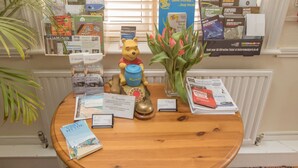Une table en bois sur laquelle sont posées des brochures, une figurine de Winnie l’ourson et un vase de fleurs.