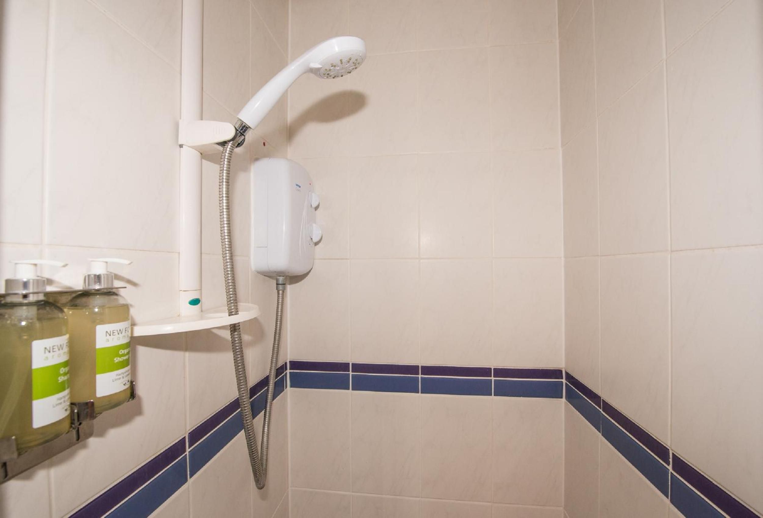 Un bagno con doccia, lavandino e due flaconi di gel doccia.