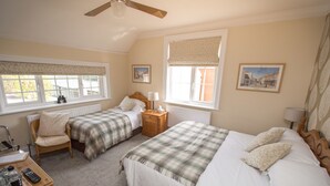 Une chambre avec deux lits, une tête de lit en bois, un ventilateur de plafond, une fenêtre avec vue et une table de chevet avec une lampe.