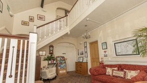 Un hall d’hôtel avec un escalier, un canapé rouge, un meuble en bois et une carte accrochée au mur.