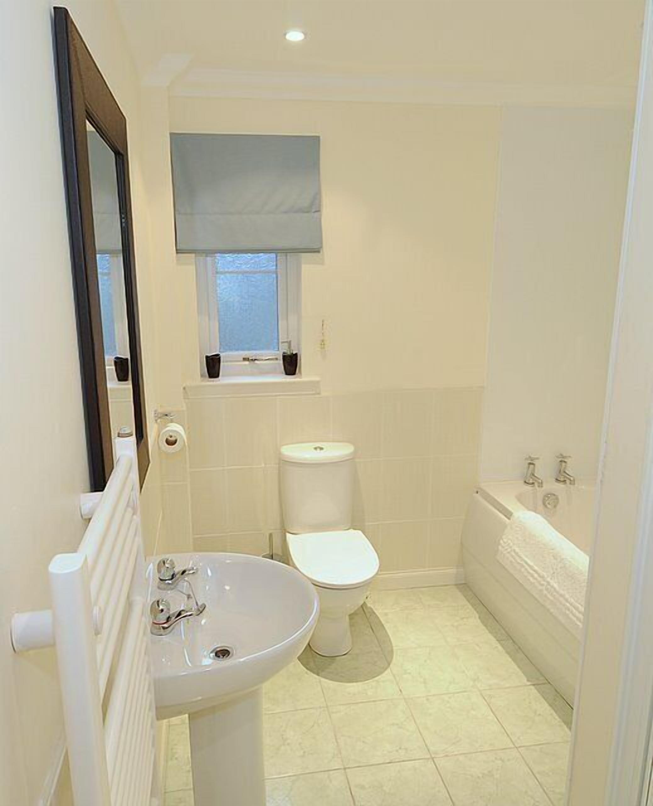 A small, clean bathroom with a white sink, toilet, and bathtub.