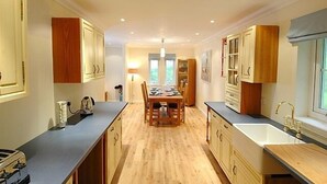 A modern kitchen with wooden cabinets, a central island, and a large window. - BCC Lochness Cottages (Inverness)