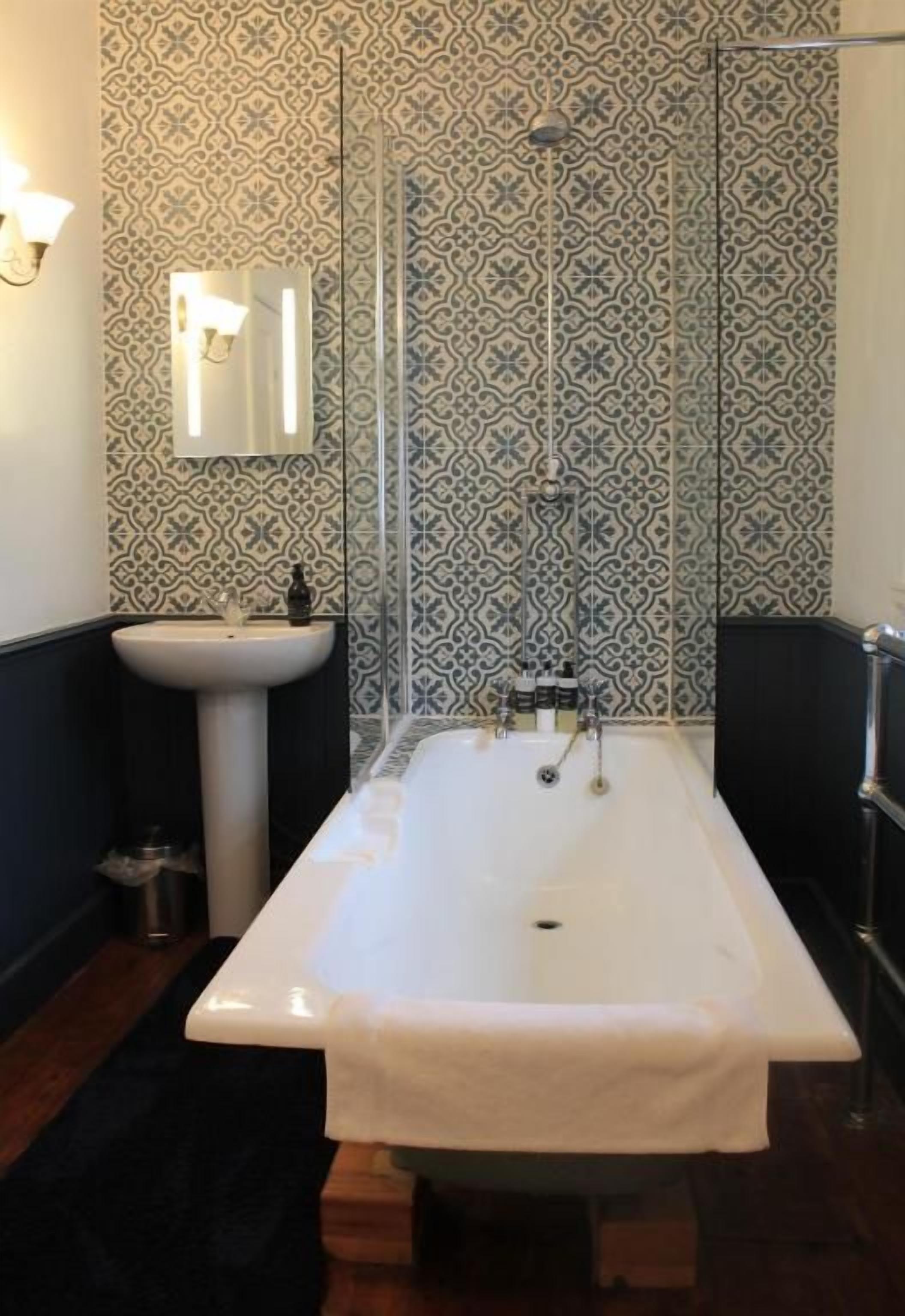 Un baño con una bañera independiente, un lavamanos y un espejo.