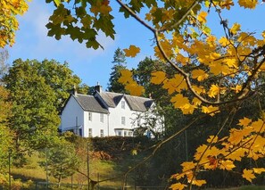A white house with a dark roof, surrounded by trees and a fence. - Tirindrish House (Spean Bridge)