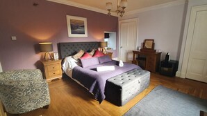 A bedroom with a bed, bedside tables, a chair, a dresser, a mirror, and a door.