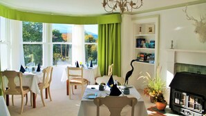 A dining area with a table set for two, a fireplace, and a bookshelf.