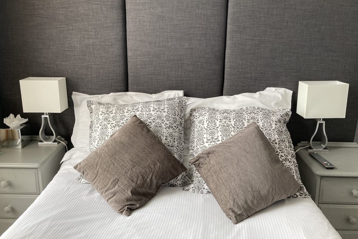 A neatly made bed with patterned pillows and two bedside tables with lamps.