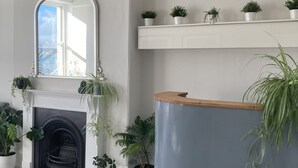 A room with a fireplace, a mirror, and several potted plants. - The Esplanade (Weymouth)