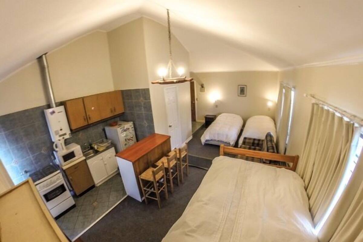 A compact room with a kitchenette, a bed, and a small seating area.