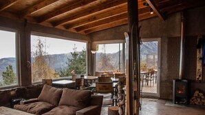 A cozy interior with a wooden ceiling, a sofa, a table, and a fireplace. - Lodge Cordillera (Lo Barnechea)