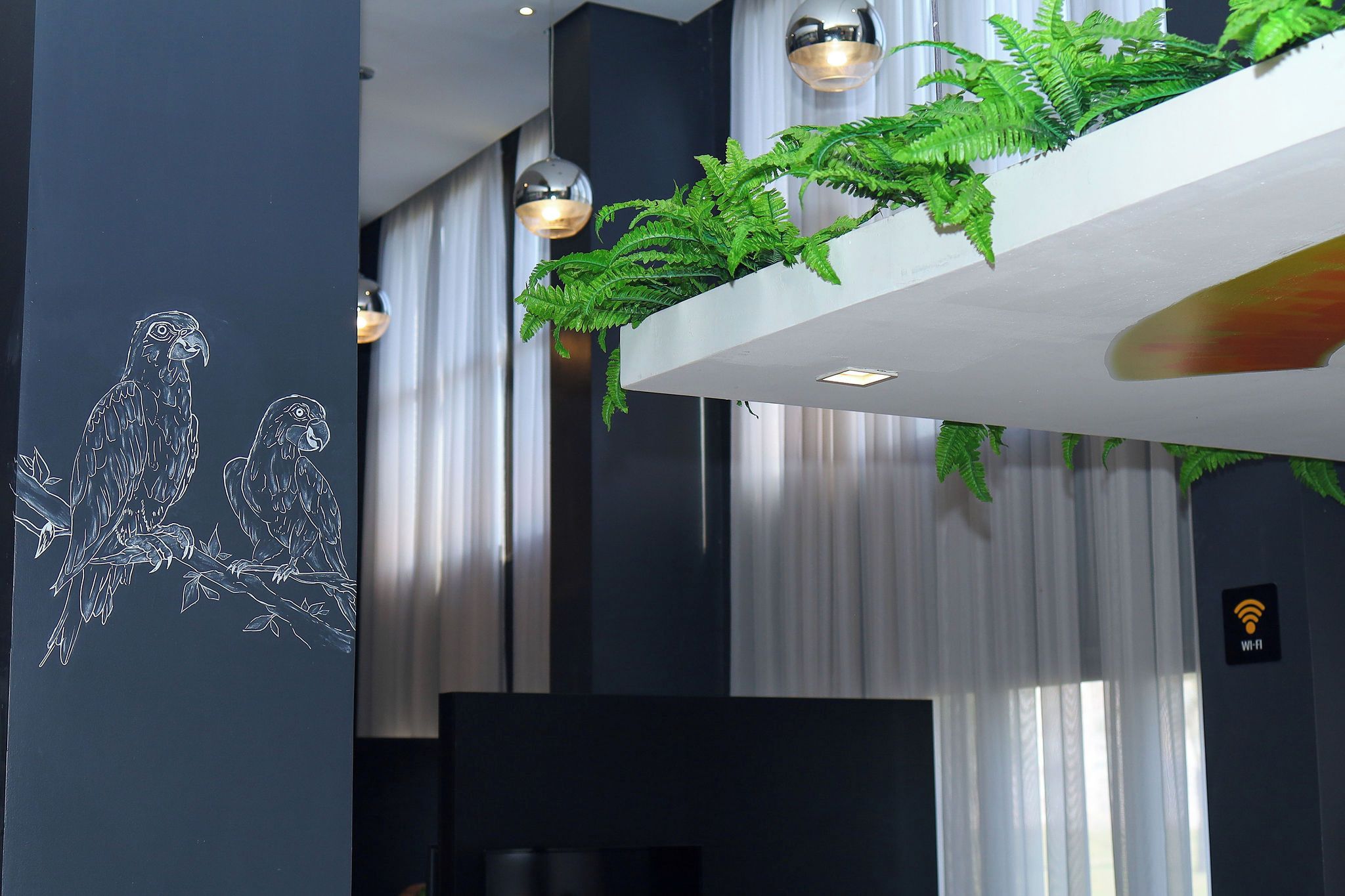 Un interno moderno con una pianta sospesa al muro, illuminazione a sospensione e simbolo Wi-Fi.
