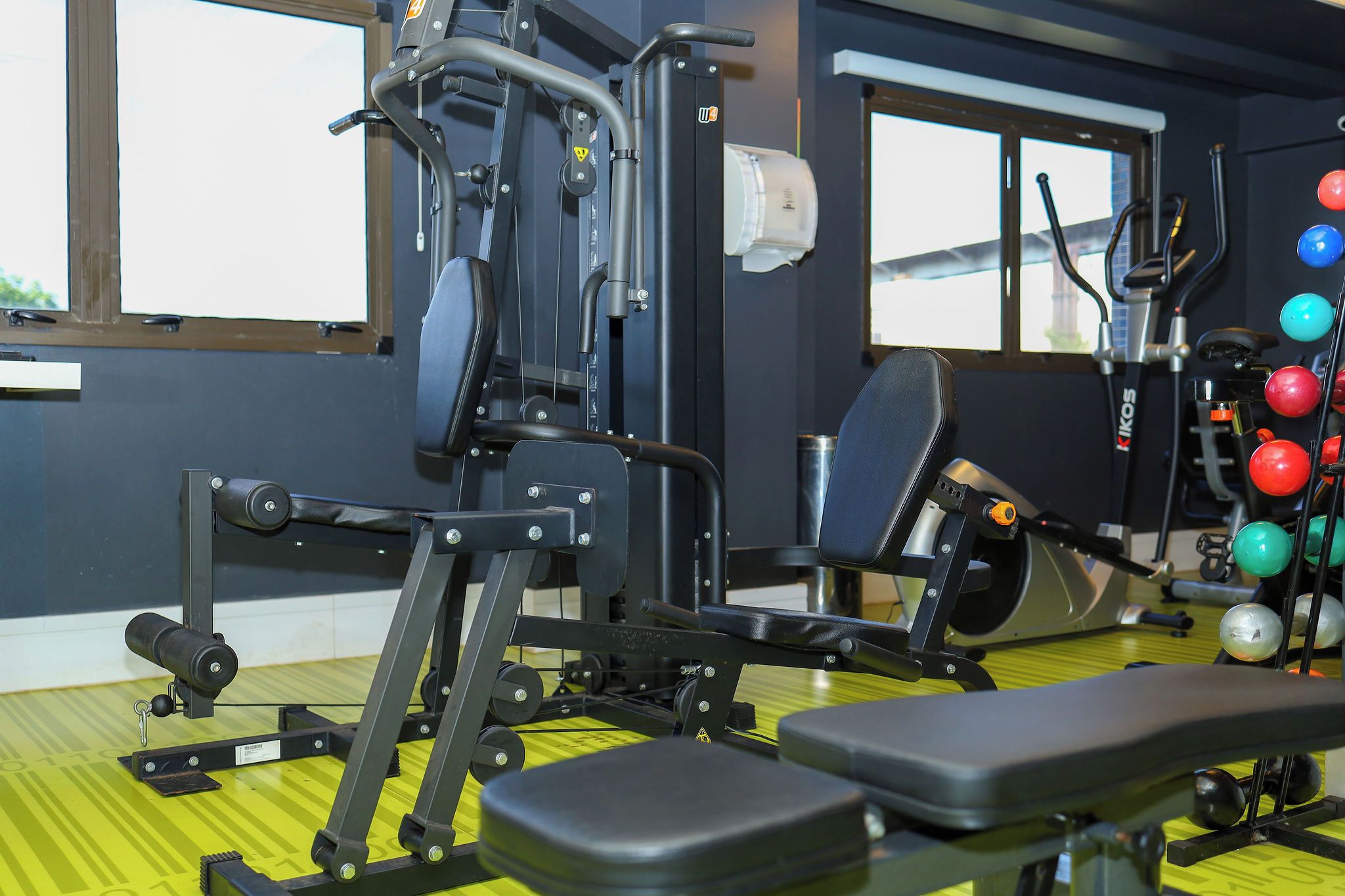 A gym with exercise equipment, a bench, and a rack of medicine balls.