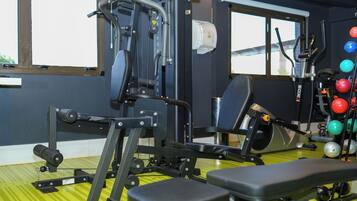 A gym with exercise equipment, a bench, and a rack of medicine balls.