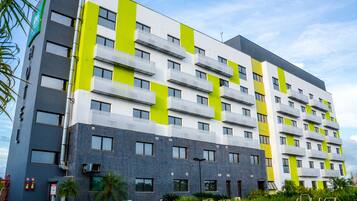 Un hotel moderno de varios pisos con balcones, piscina y un jardín bien cuidado.