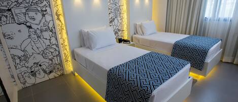Una habitación de hotel con dos camas, una pared con un mural blanco y negro, y una ventana con cortinas.