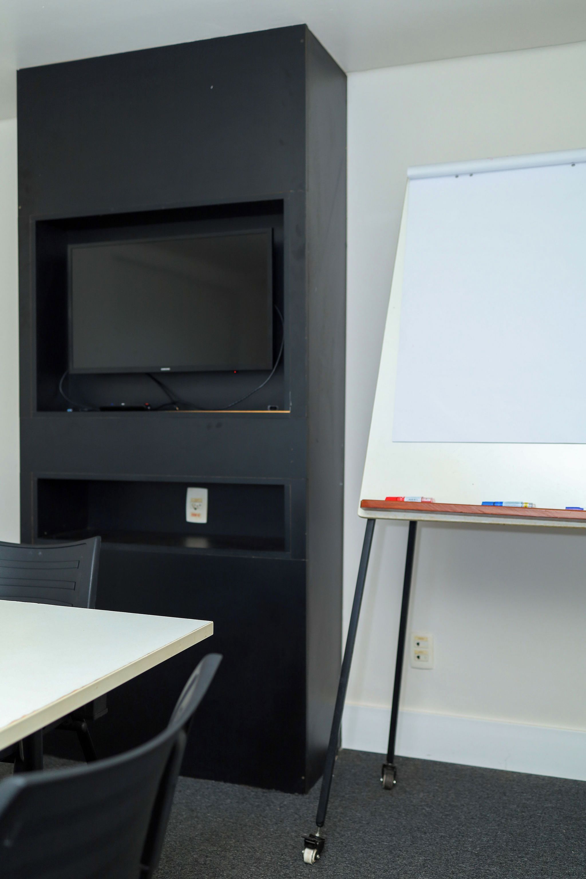 A conference room with a flat-screen TV, a whiteboard, and a table with chairs.