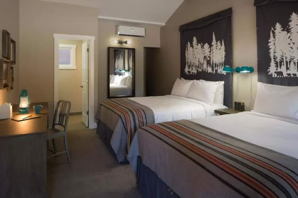 Une chambre d’hôtel avec deux lits, un bureau, une chaise et un miroir.