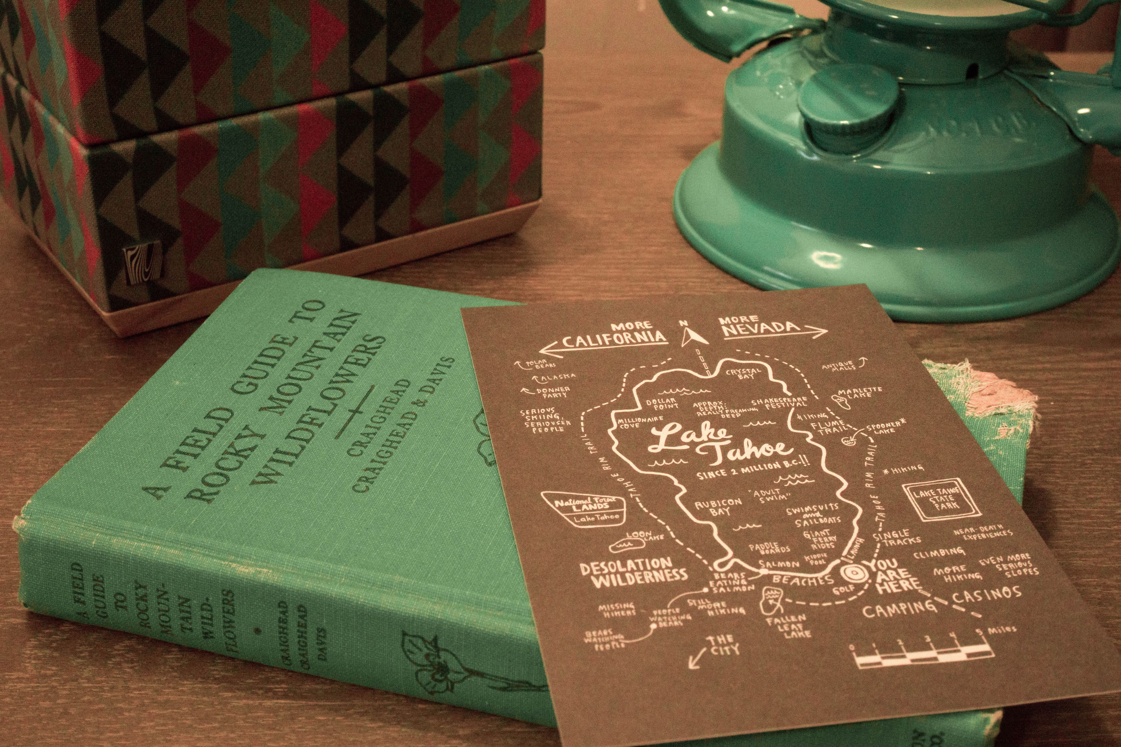 A book titled 'A Field Guide to Rocky Mountain Wildflowers' and a map of Lake Tahoe.