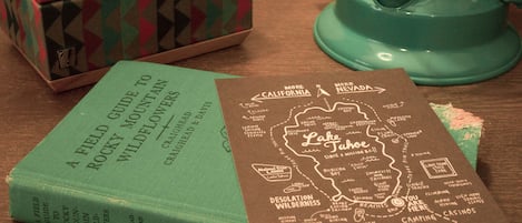 A book titled 'A Field Guide to Rocky Mountain Wildflowers' and a map of Lake Tahoe.