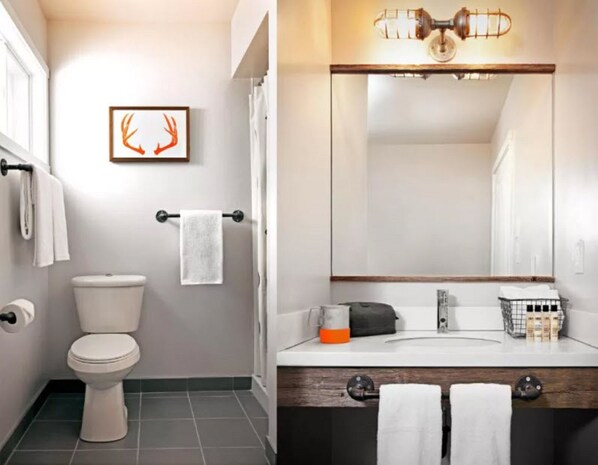 A modern bathroom with a toilet, a towel rack, a framed deer antler artwork, and a sink with a mirror above it.