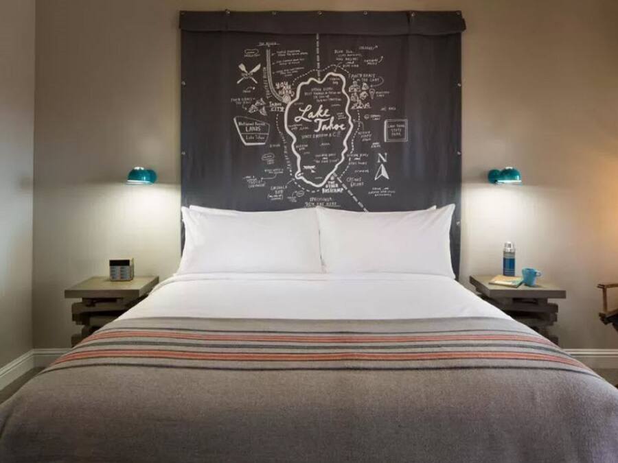 Ein Hotelzimmer mit einem Bett, zwei Nachttischen, einer Kopfteil mit einer Karte und zwei Wandlampen.