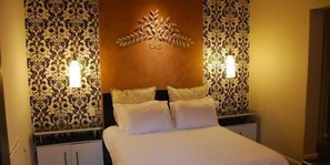 A hotel room with a bed, two nightstands, and patterned wallpaper.