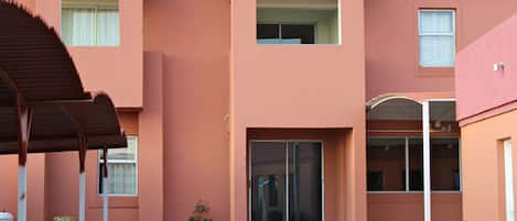 A building with a red exterior, a covered entrance, and a small garden area with plants.